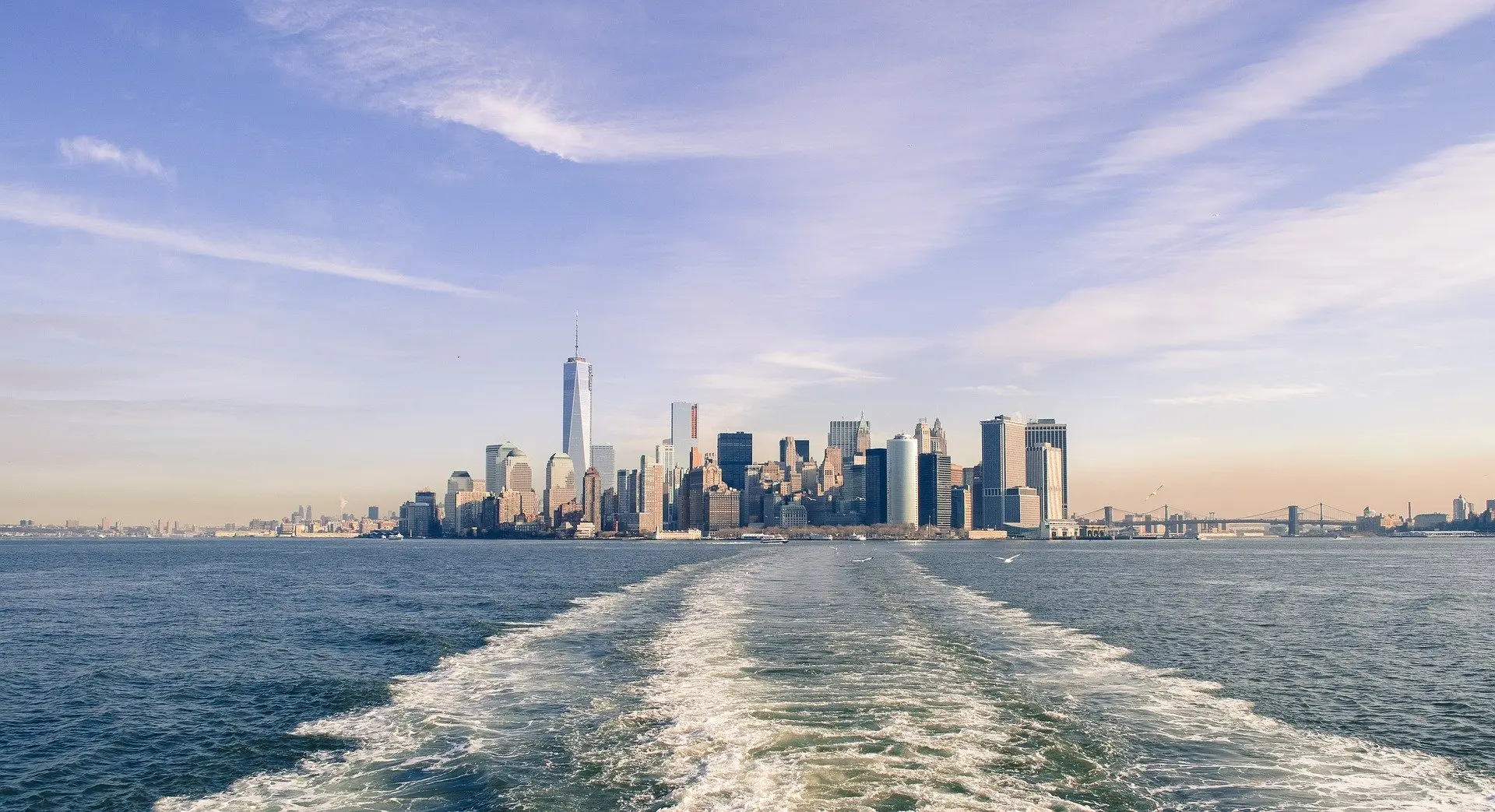 Lower Manhattan skyline seen from the water behind a boat wake